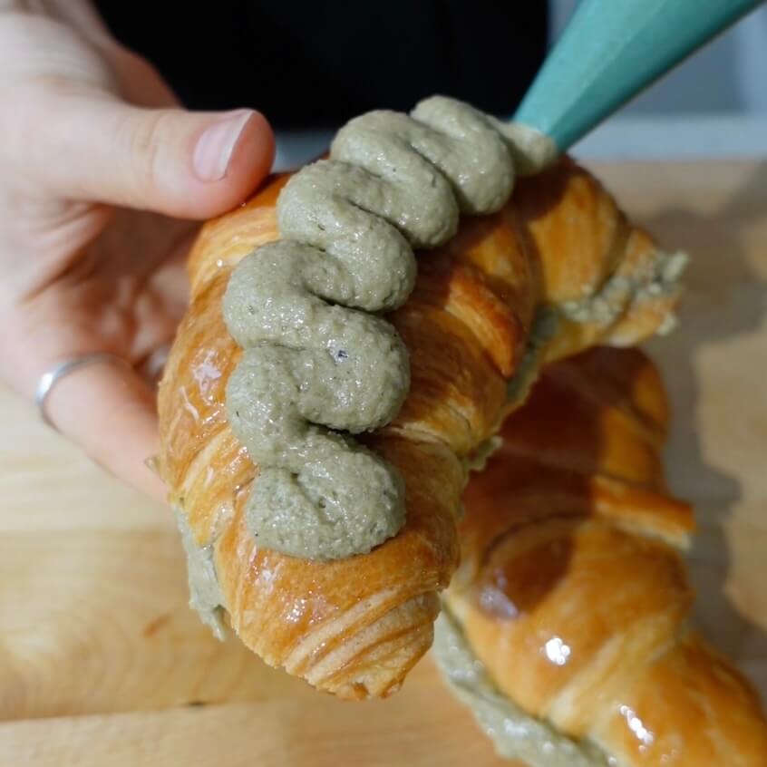 Piping matcha frangipane on top of croissant